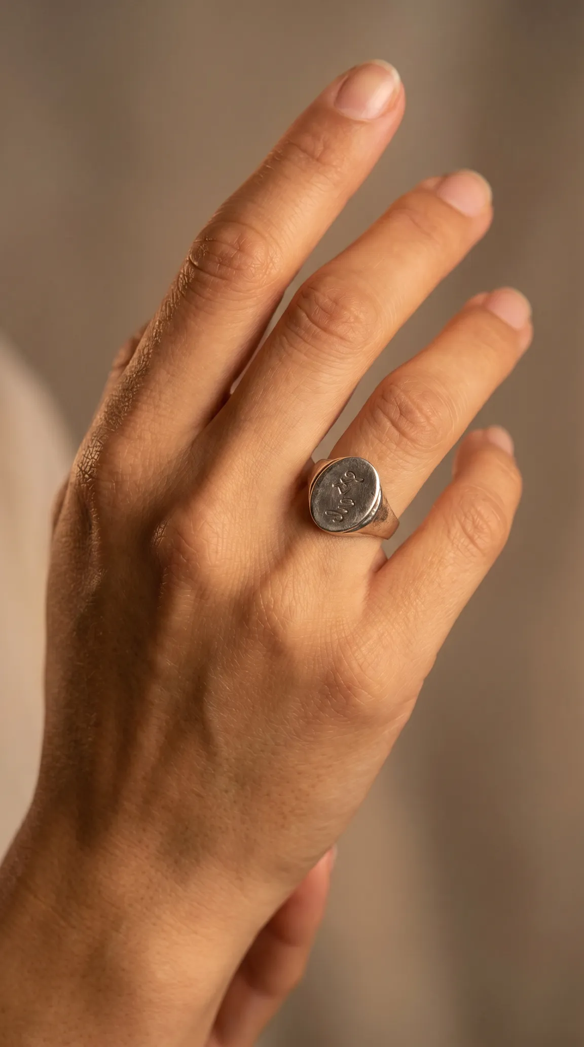 Vintage sterling silver signet ring with engraved design on a hand