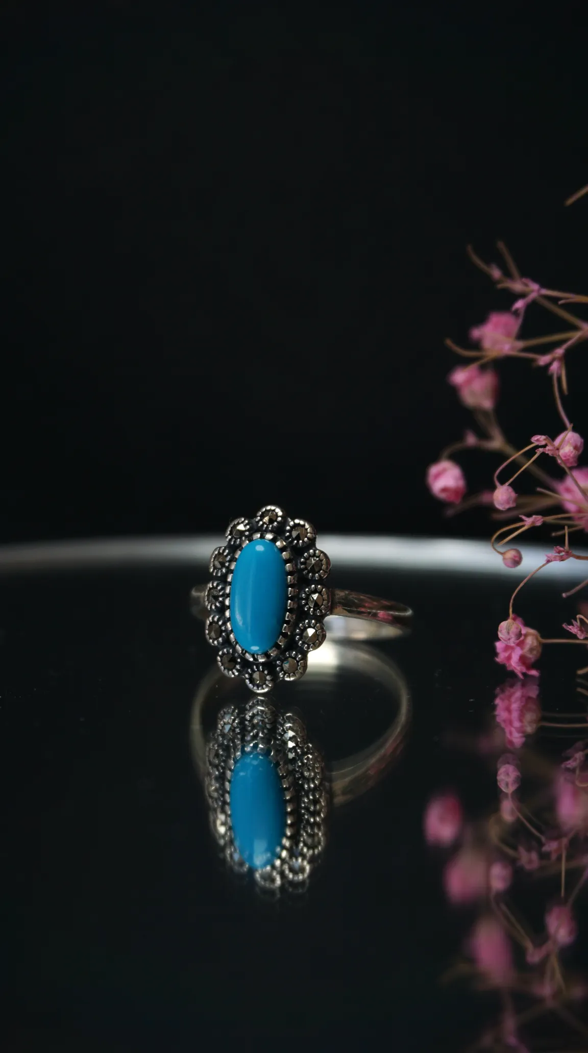 Vintage sterling silver ring with oval turquoise gemstone and marcasite halo.