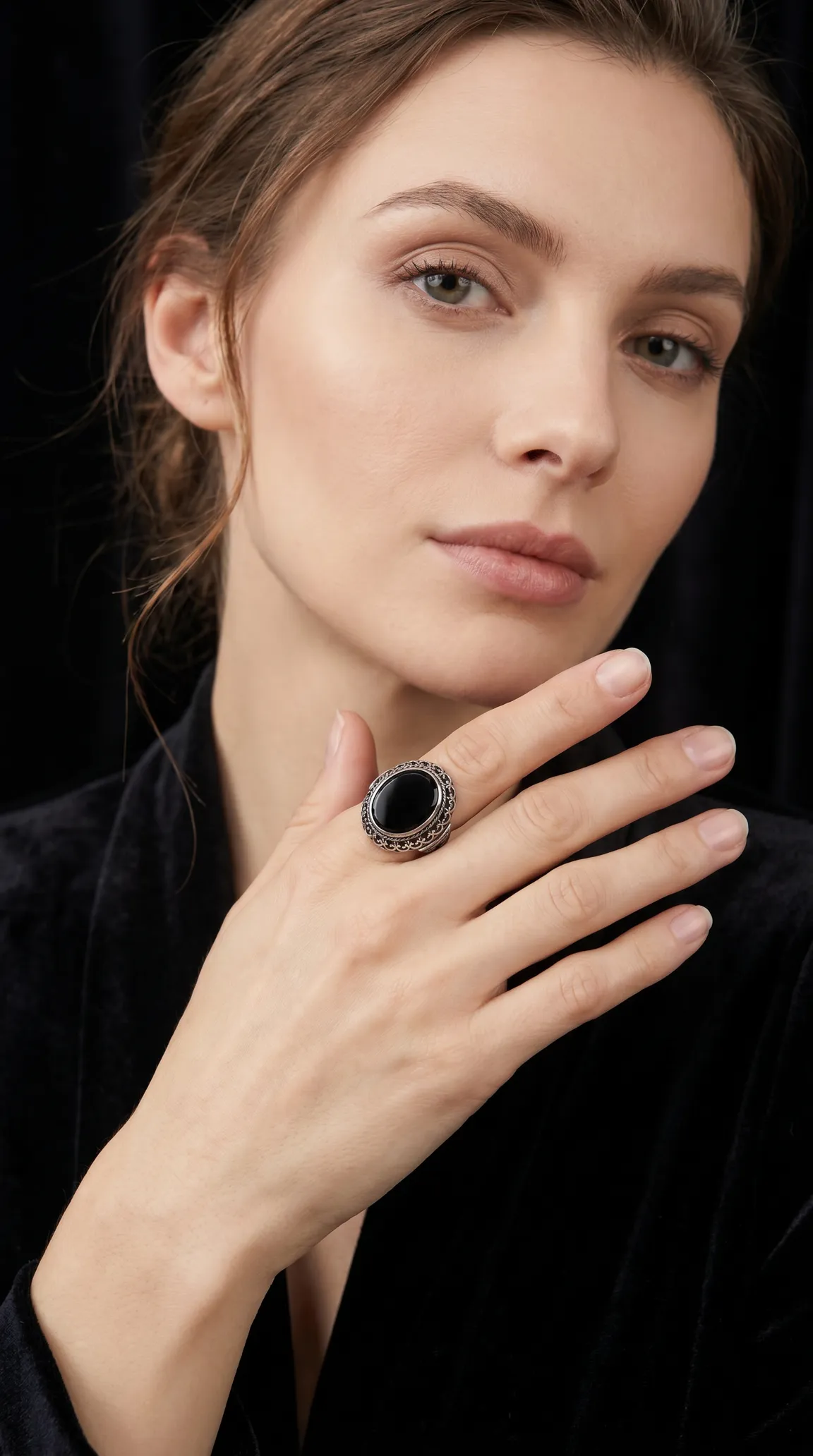 Vintage ornate silver ring with oval black onyx stone on elegant woman's hand.