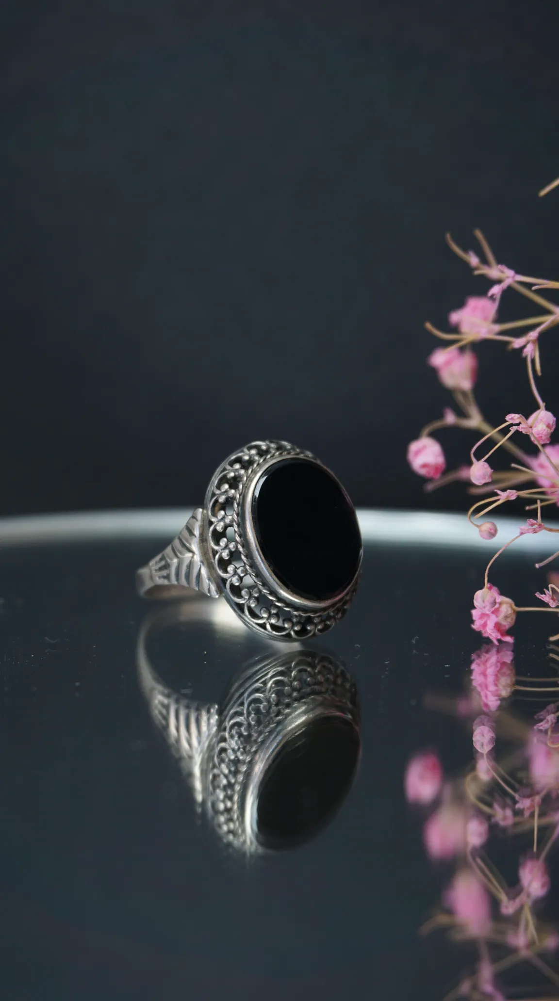 Vintage sterling silver ring with black oval onyx gemstone, featuring ornate filigree detailing.