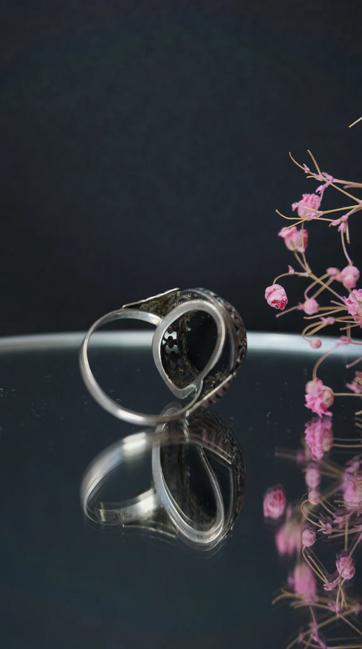 Vintage silver ring with black gemstone and ornate scrolled design