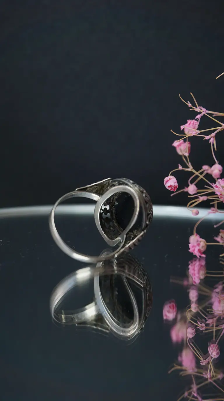 Vintage silver ring with black gemstone and ornate scrolled design