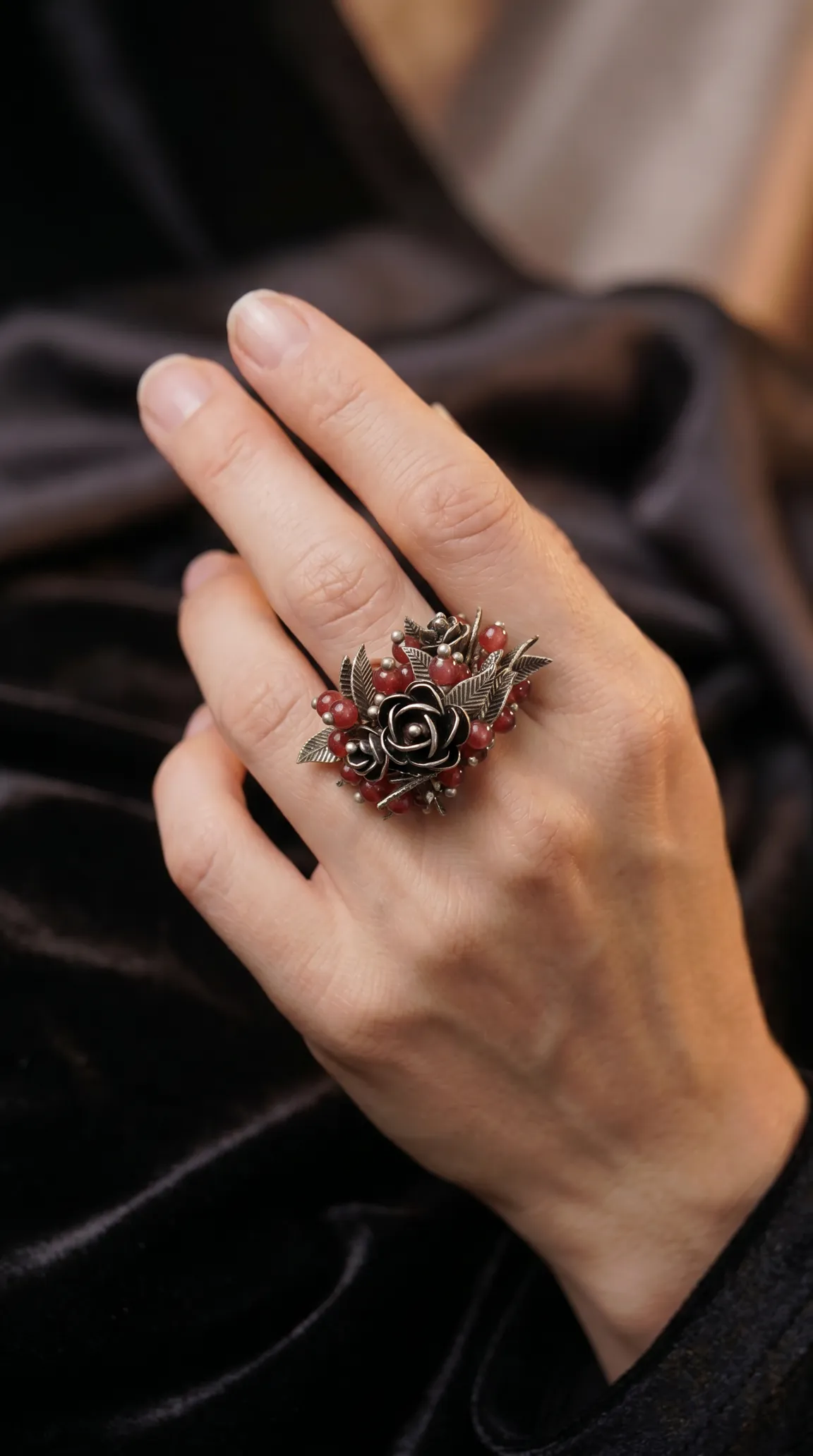 Vintage oxidized silver floral rose cluster ring with red beads and leaves on a hand.