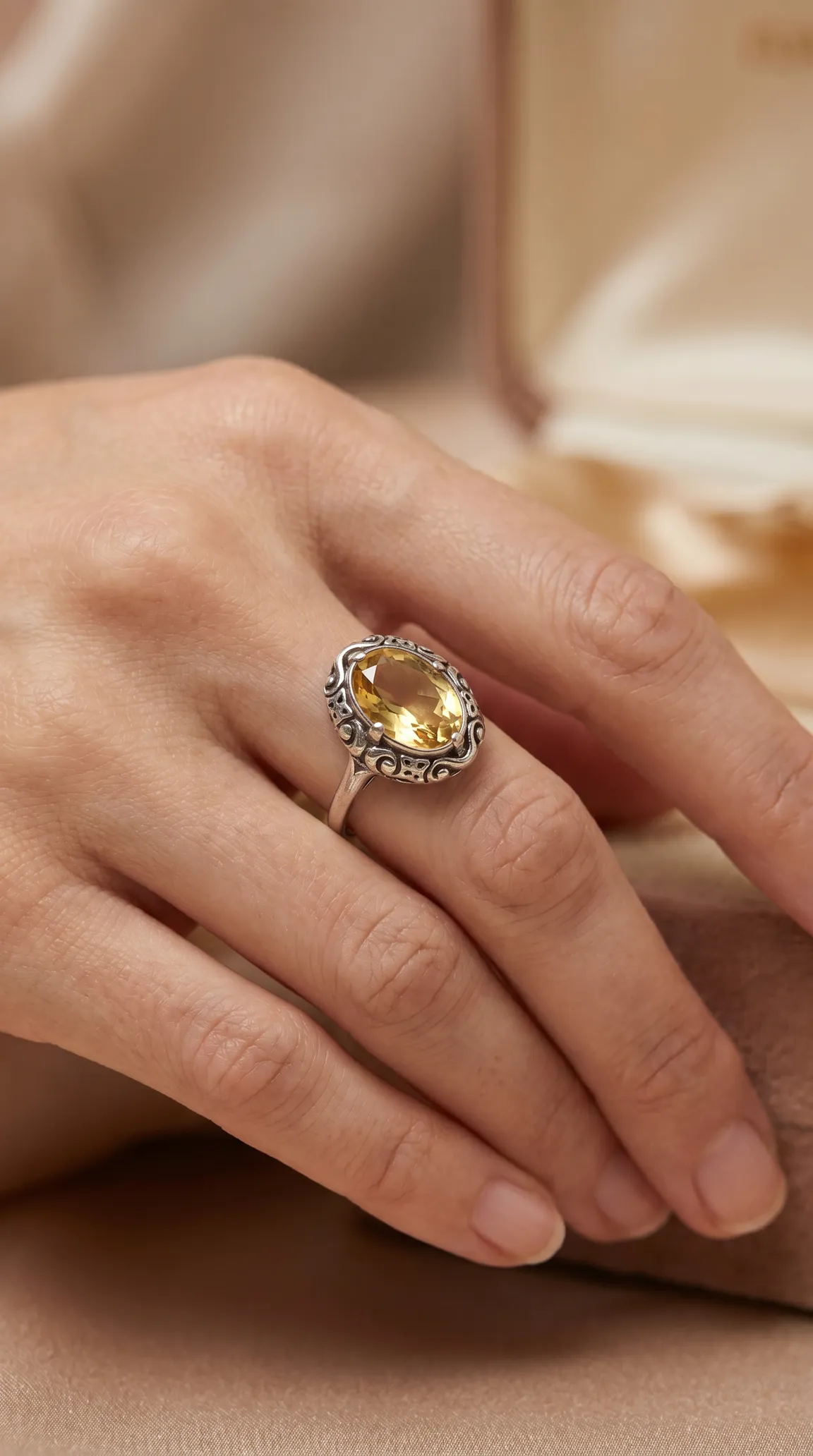 Vintage sterling silver ring with oval yellow citrine gemstone, ornate filigree design, worn on a hand.