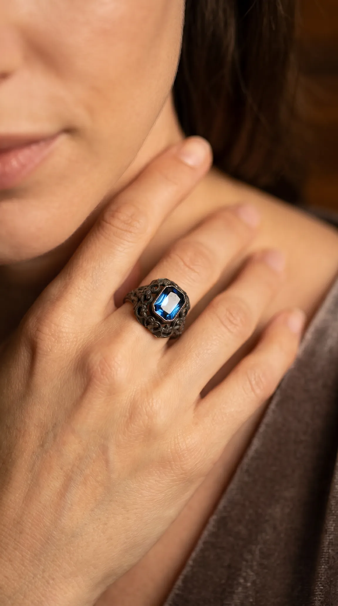 Vintage blue gemstone ring with intricate dark metalwork on a woman's hand