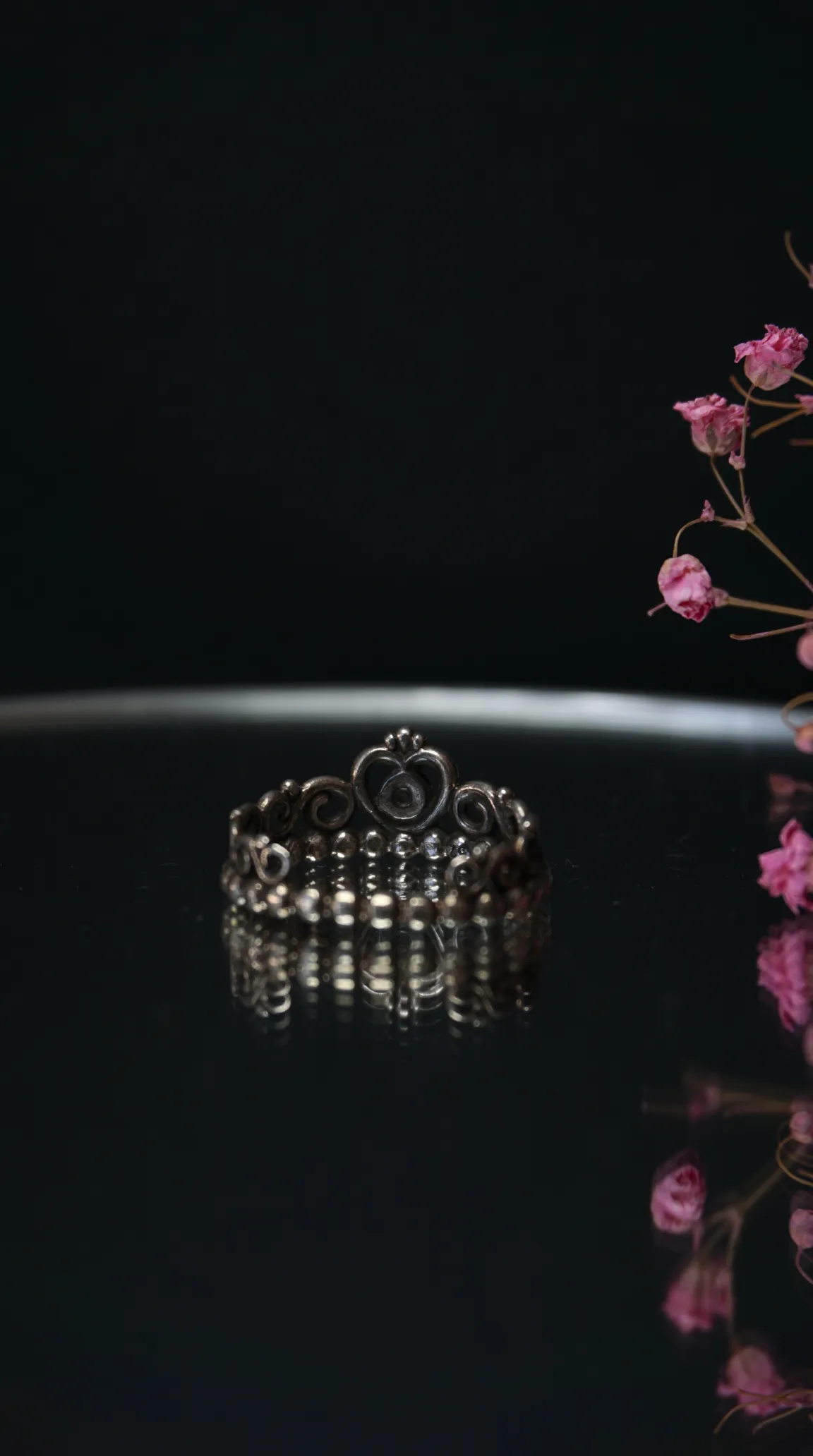vintage silver crown ring with heart detail on dark reflective surface
