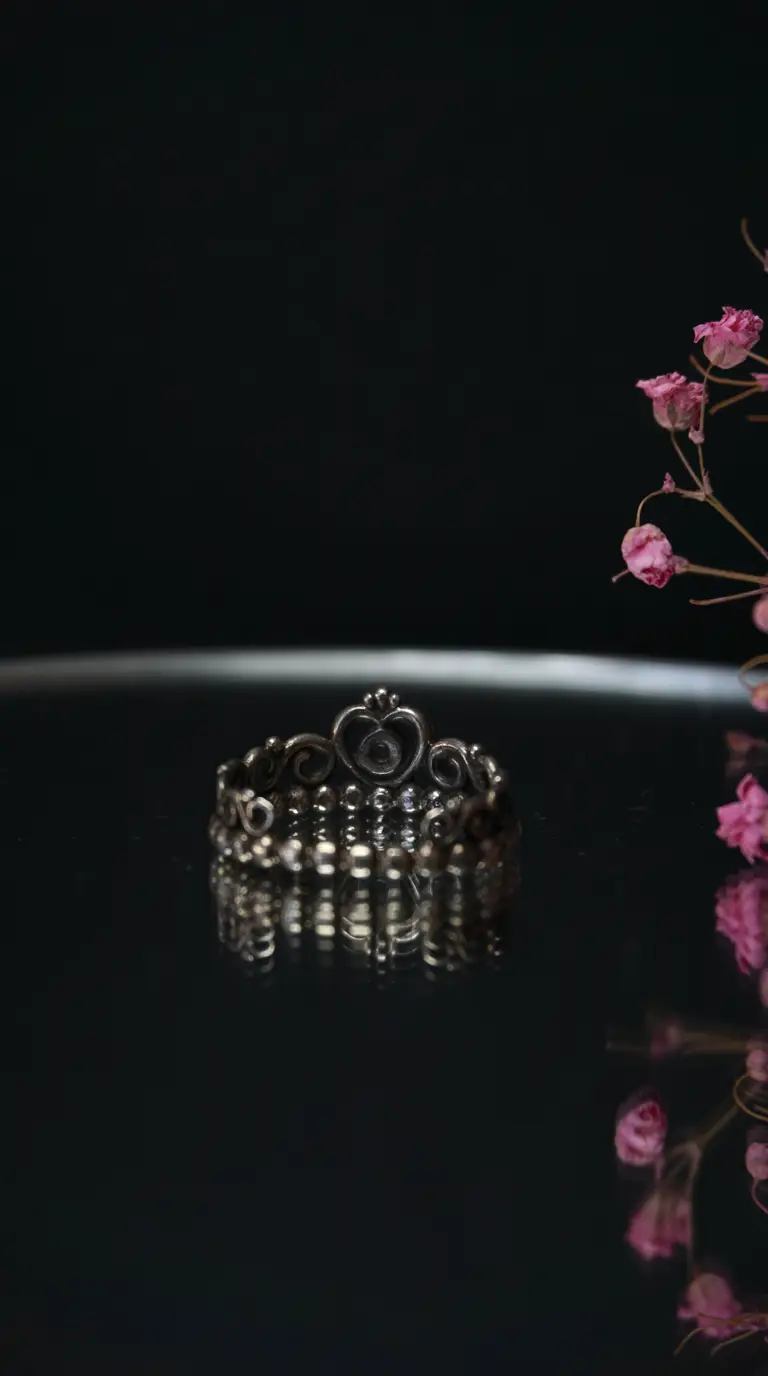 vintage silver crown ring with heart detail on dark reflective surface