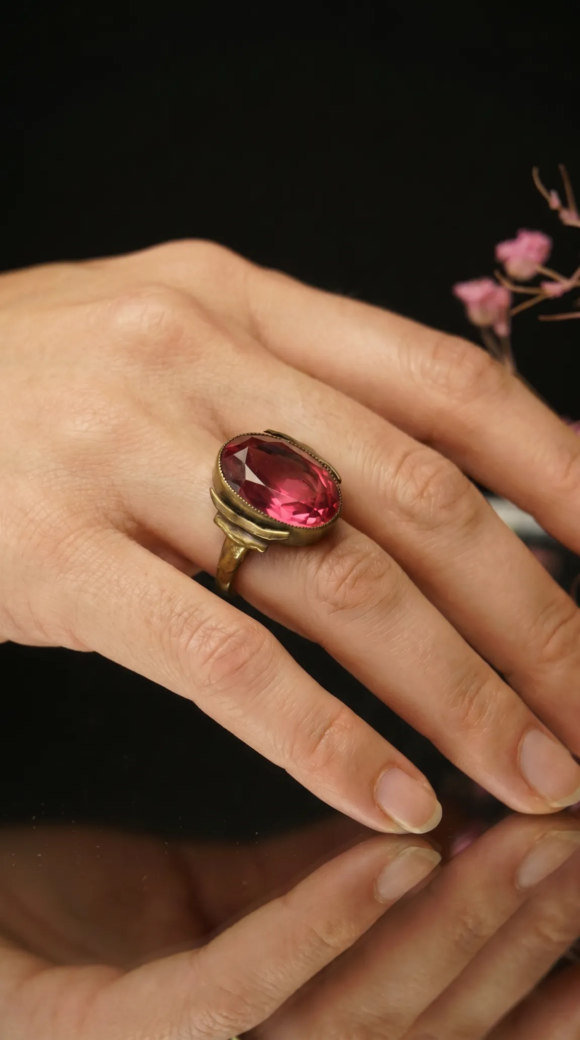 Vintage oval pink gemstone ring with antique gold tone setting on a woman's hand