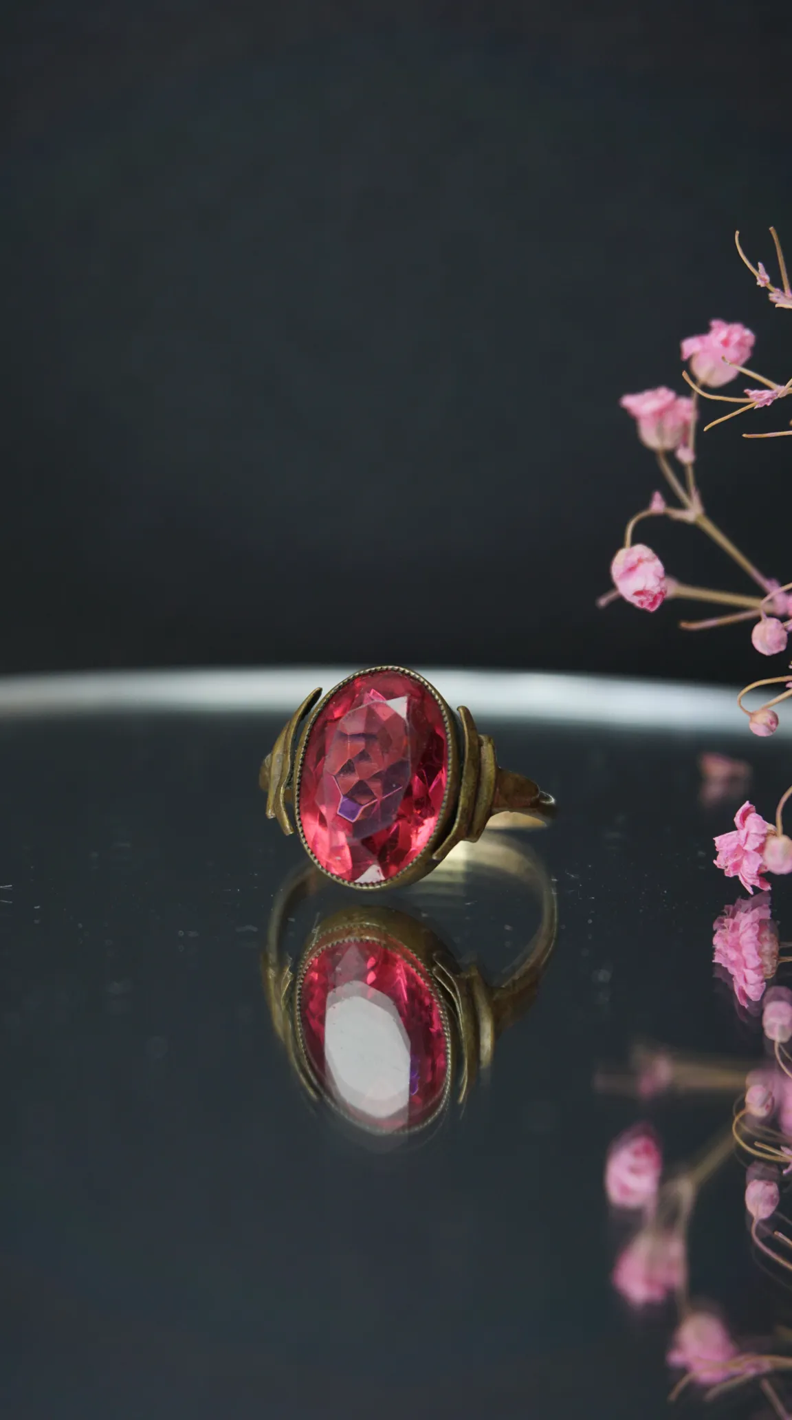 Vintage oval faceted pink gemstone ring with antique gold-tone band.