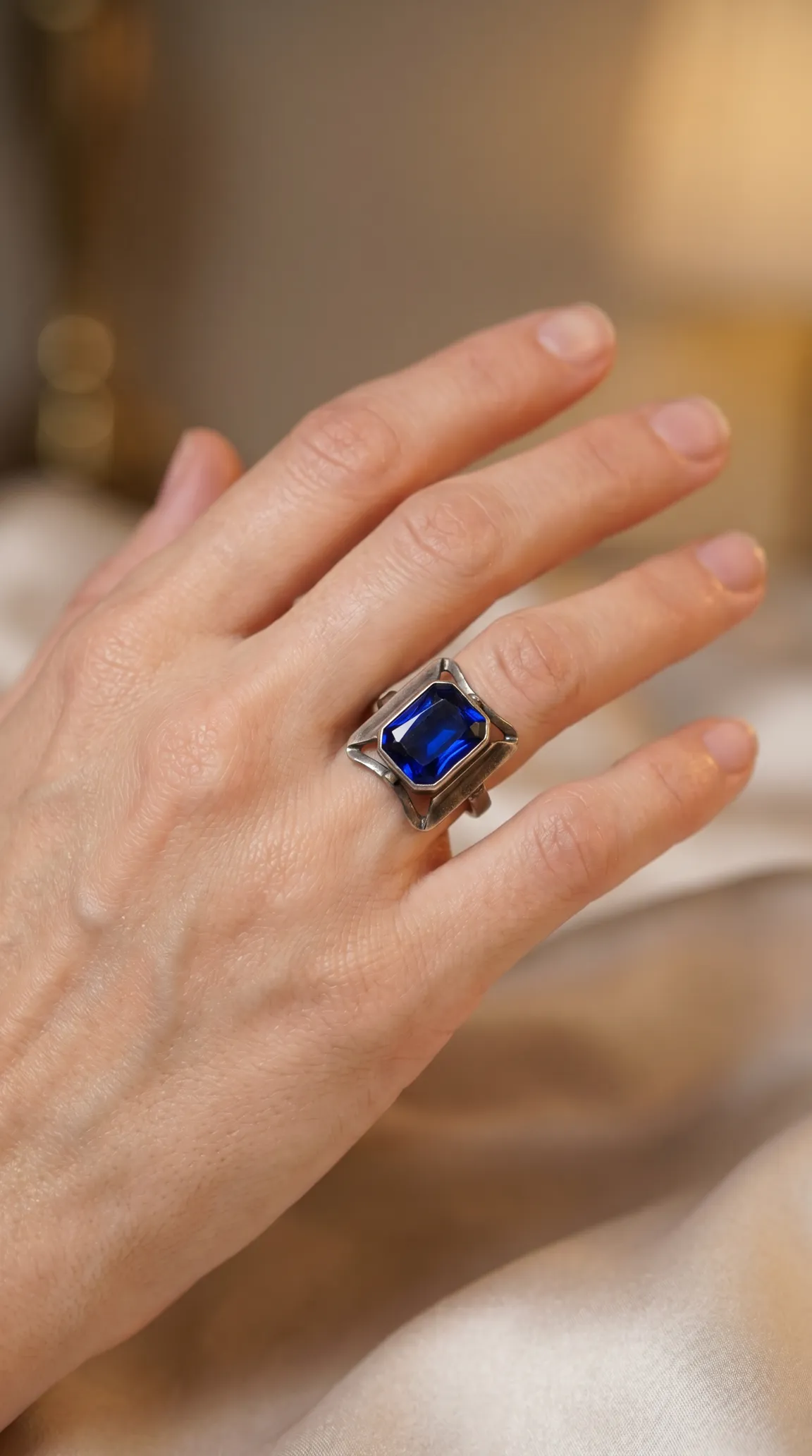 Vintage silver ring with large rectangular blue gemstone worn on hand