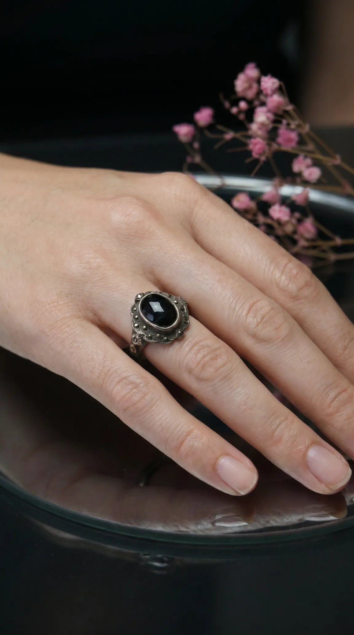 Vintage sterling silver ring with oval black onyx gemstone and marcasite accents on a woman's hand.