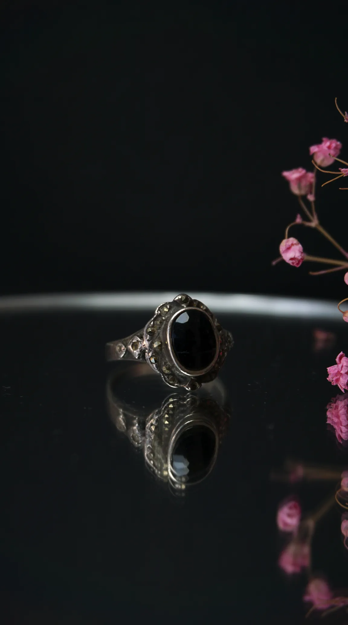 Vintage silver ring with oval black onyx gemstone and marcasite accents.