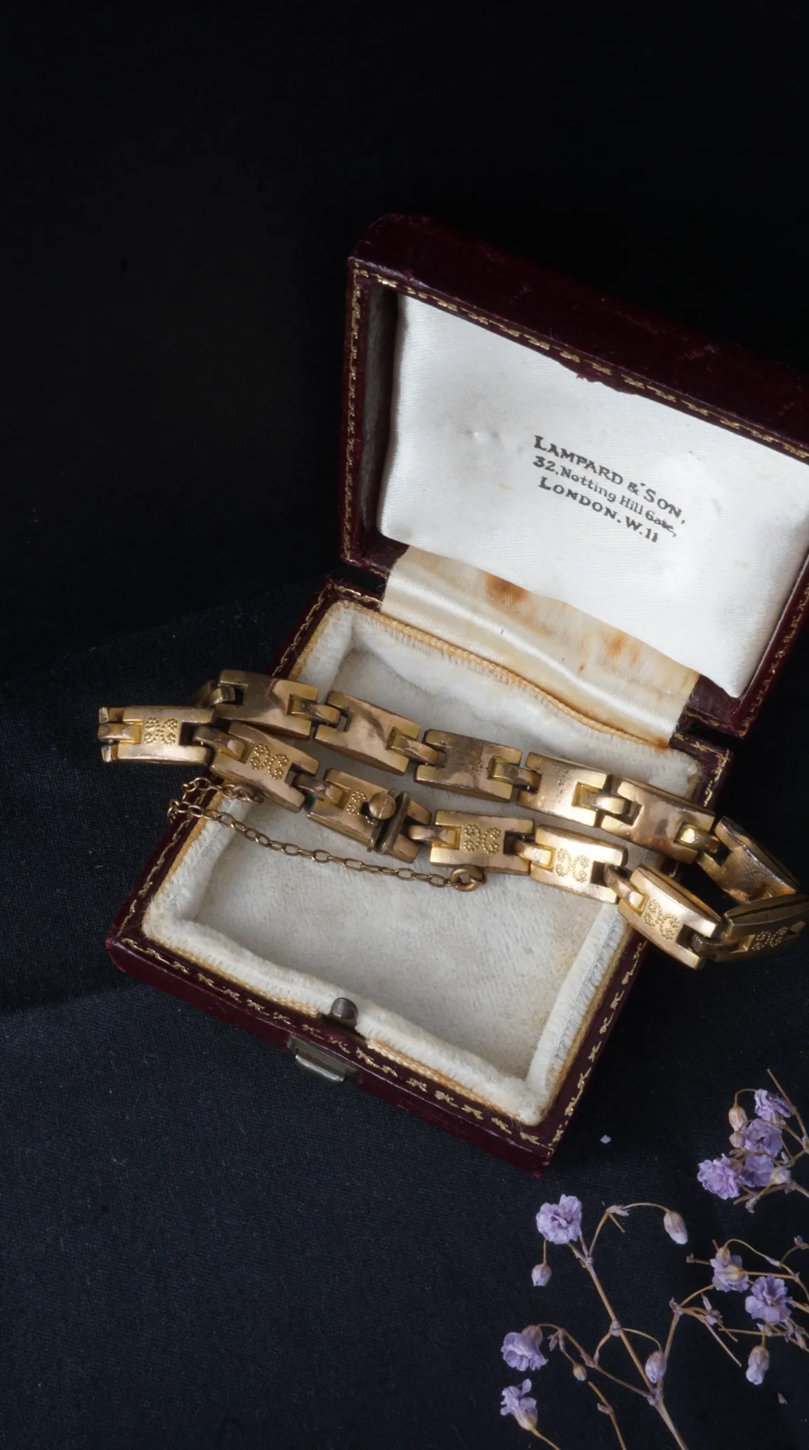 Antique gold link bracelet with engraved design and safety chain, showcased in vintage Lampard & Son London jewelry box.