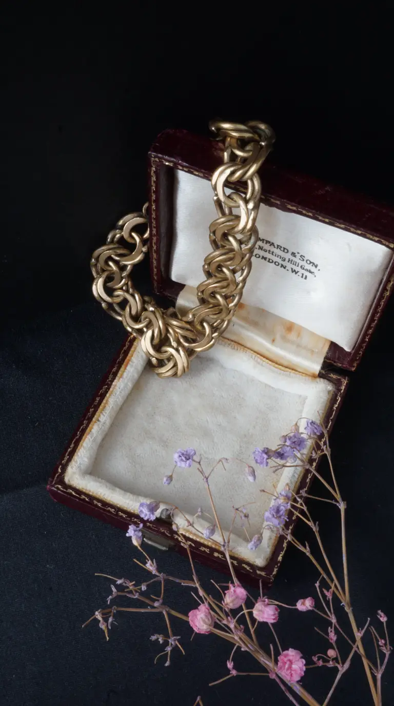 Vintage gold chunky chain bracelet in open red leather BAMPARD & SON Notting Hill Gate London jewelry box with dried purple flowers.