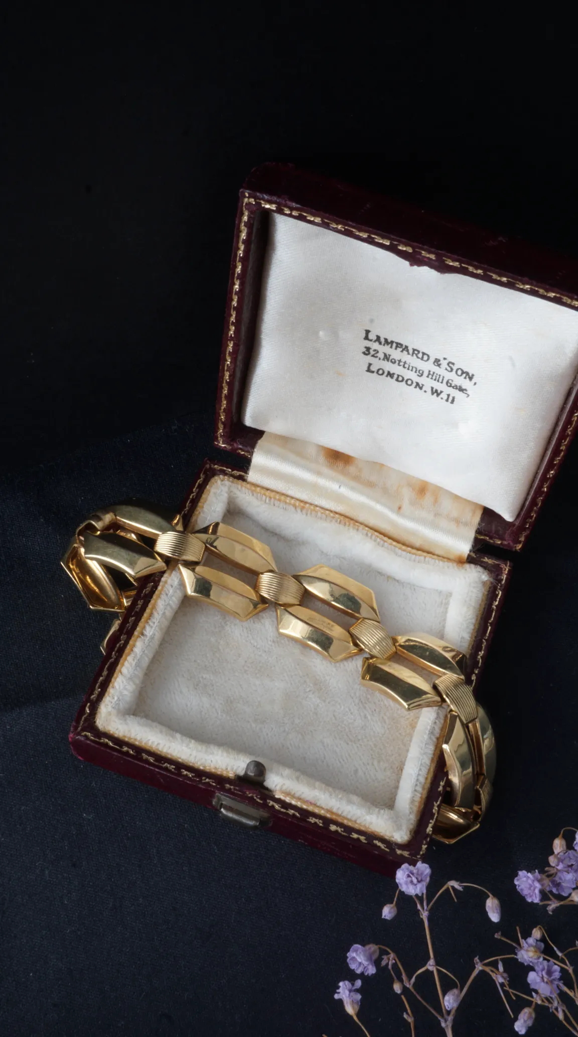 Vintage Art Deco gold link bracelet with textured and polished segments, displayed in a red velvet Lampard & Son London jewelry box.