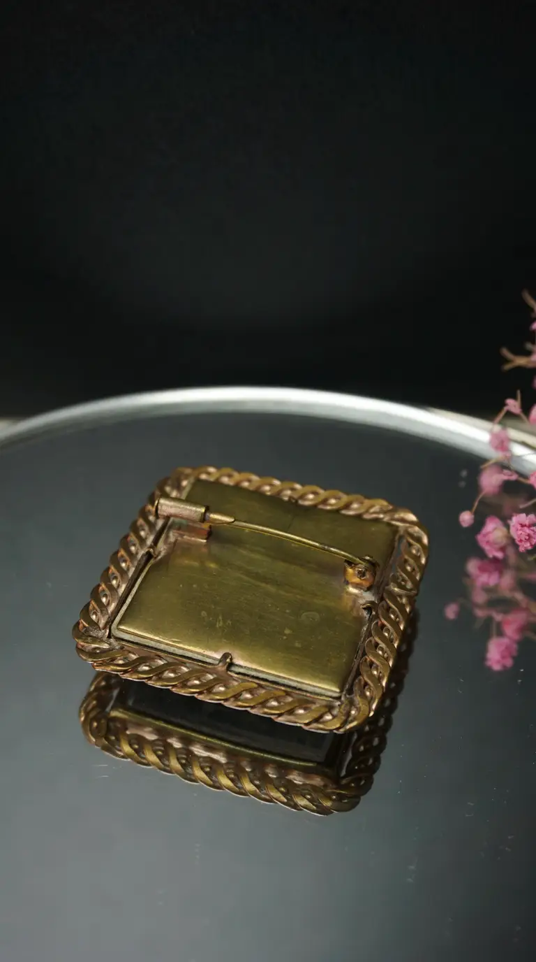 Vintage brass rectangular brooch back with twisted rope border and pin mechanism.
