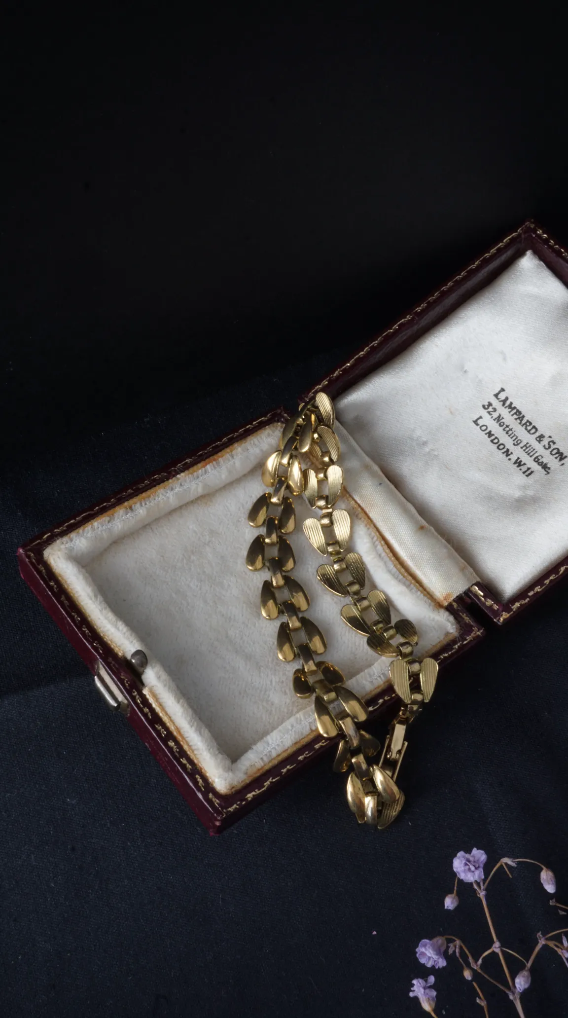 Vintage gold-tone link bracelet with engraved heart-shaped links in open burgundy Lampard & Son jewelry box.