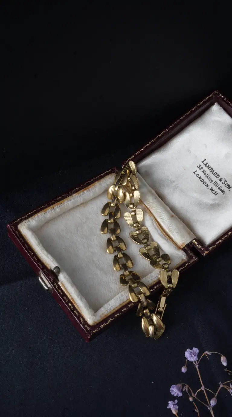 Vintage gold-tone link bracelet with engraved heart-shaped links in open burgundy Lampard & Son jewelry box.