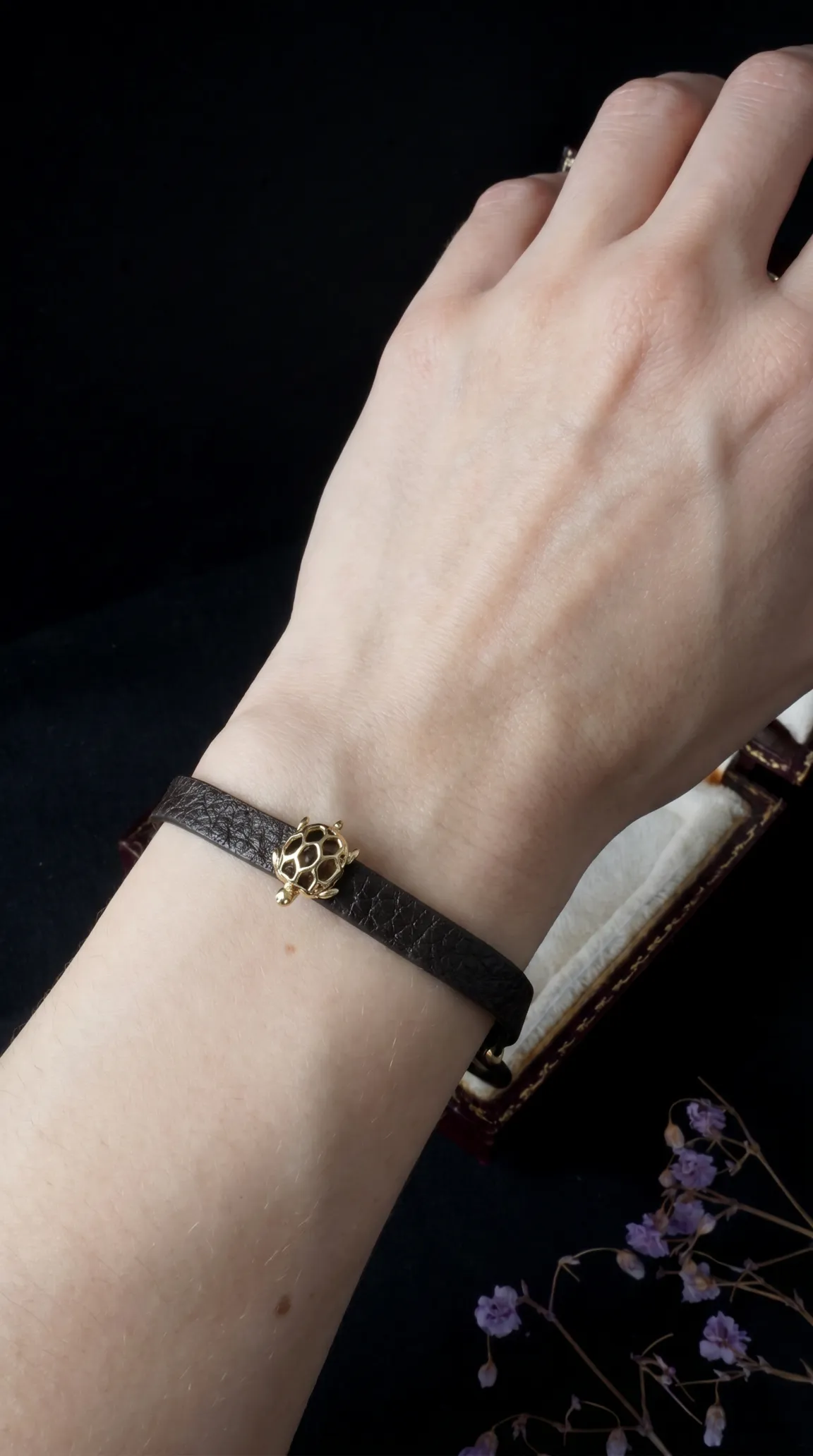 Vintage brown leather bracelet with gold turtle charm on wrist