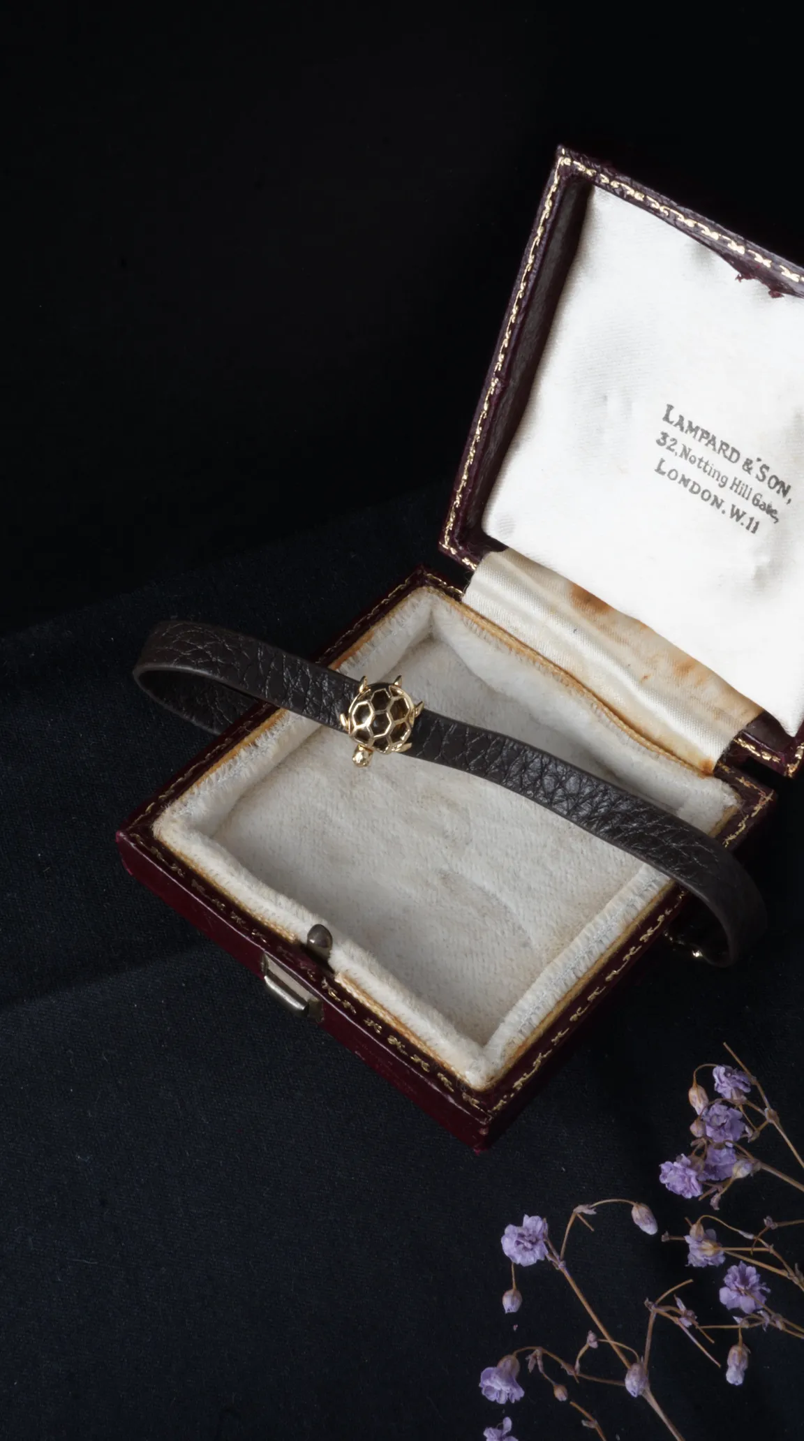 Vintage dark brown leather bracelet with gold tortoise charm, in an antique Lampard & Son jewelry box from London.