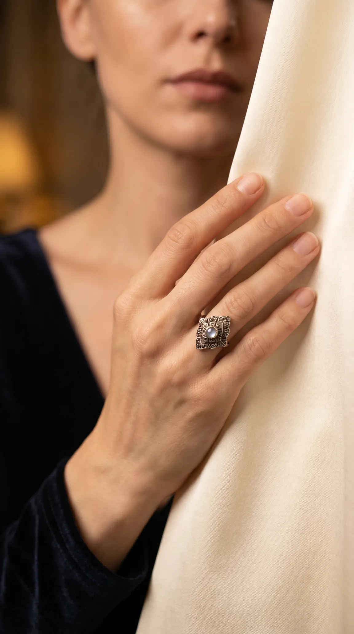 Vintage moonstone ring with intricate silver details on a woman's hand.