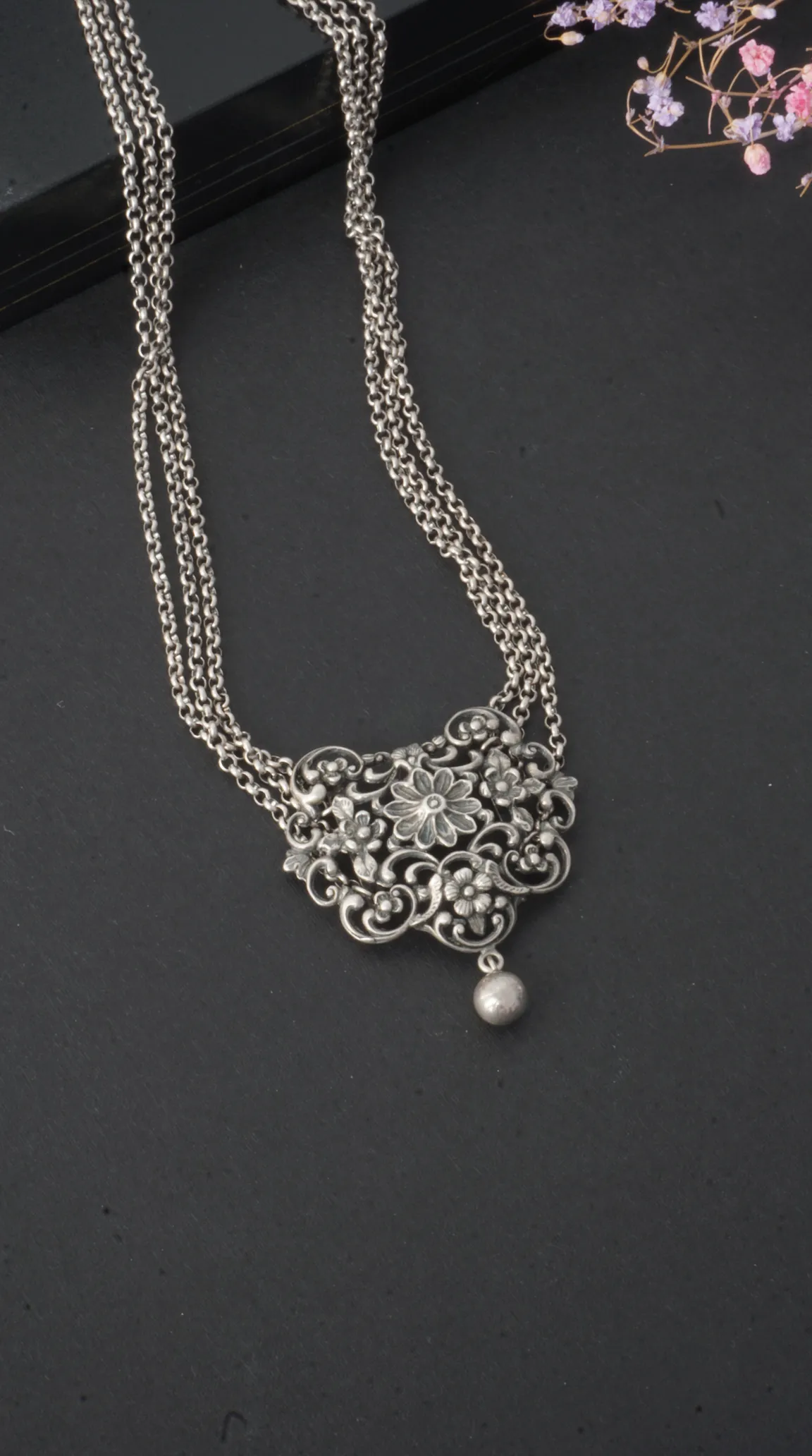 Vintage oxidized silver floral pendant necklace with multiple chains and dangling bead, handcrafted antique jewelry for women.
