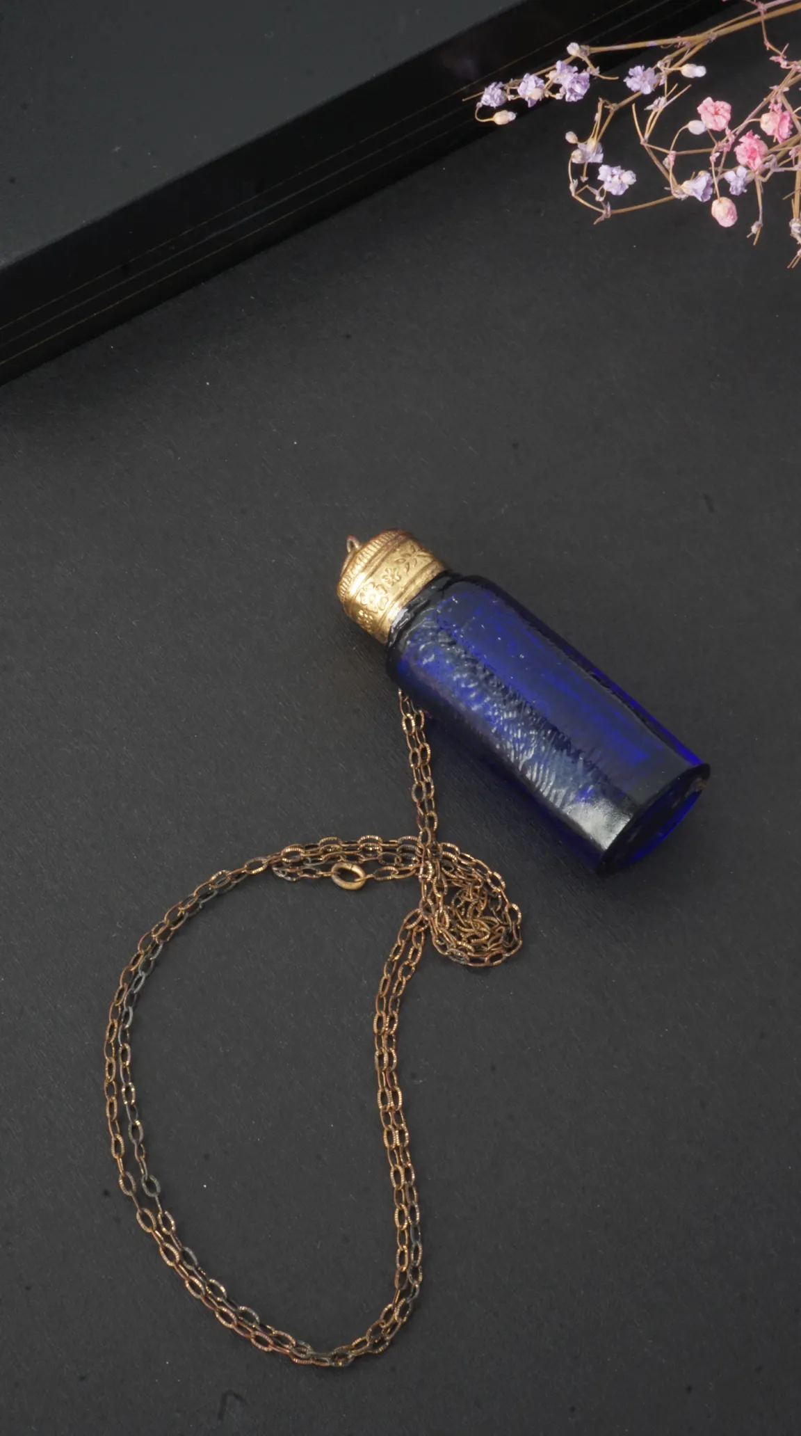 Vintage blue glass perfume bottle pendant necklace with ornate gold-tone cap and delicate aged brass chain