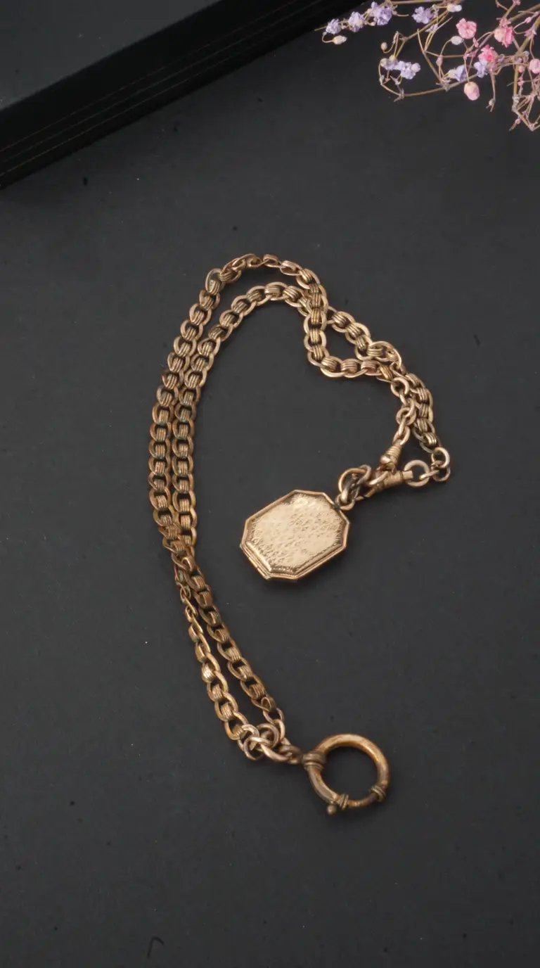 Vintage gold tone fob chain with engraved octagonal locket and textured links.