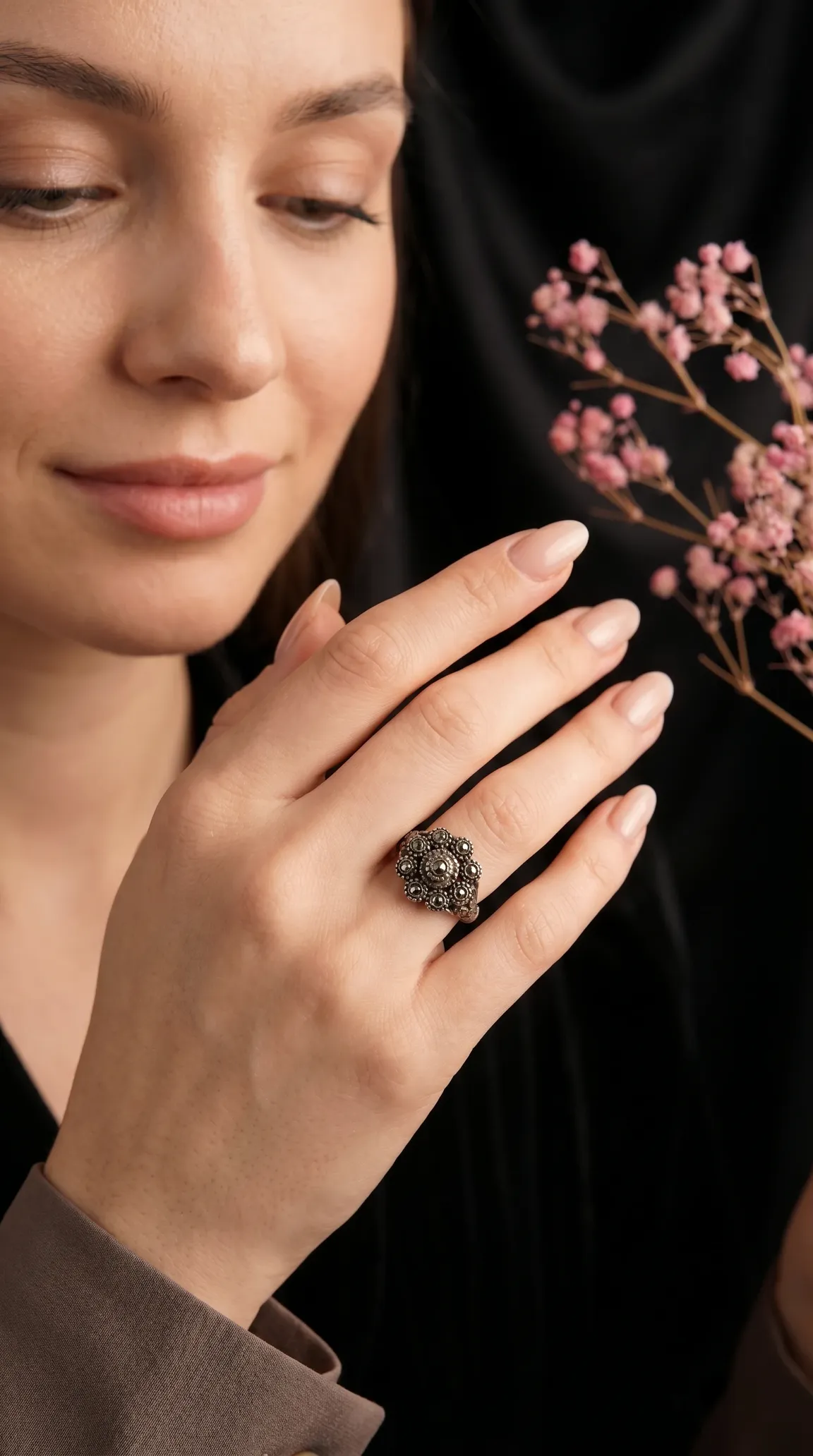 Vintage ornate floral cluster ring on woman's hand holding pink baby's breath flowers