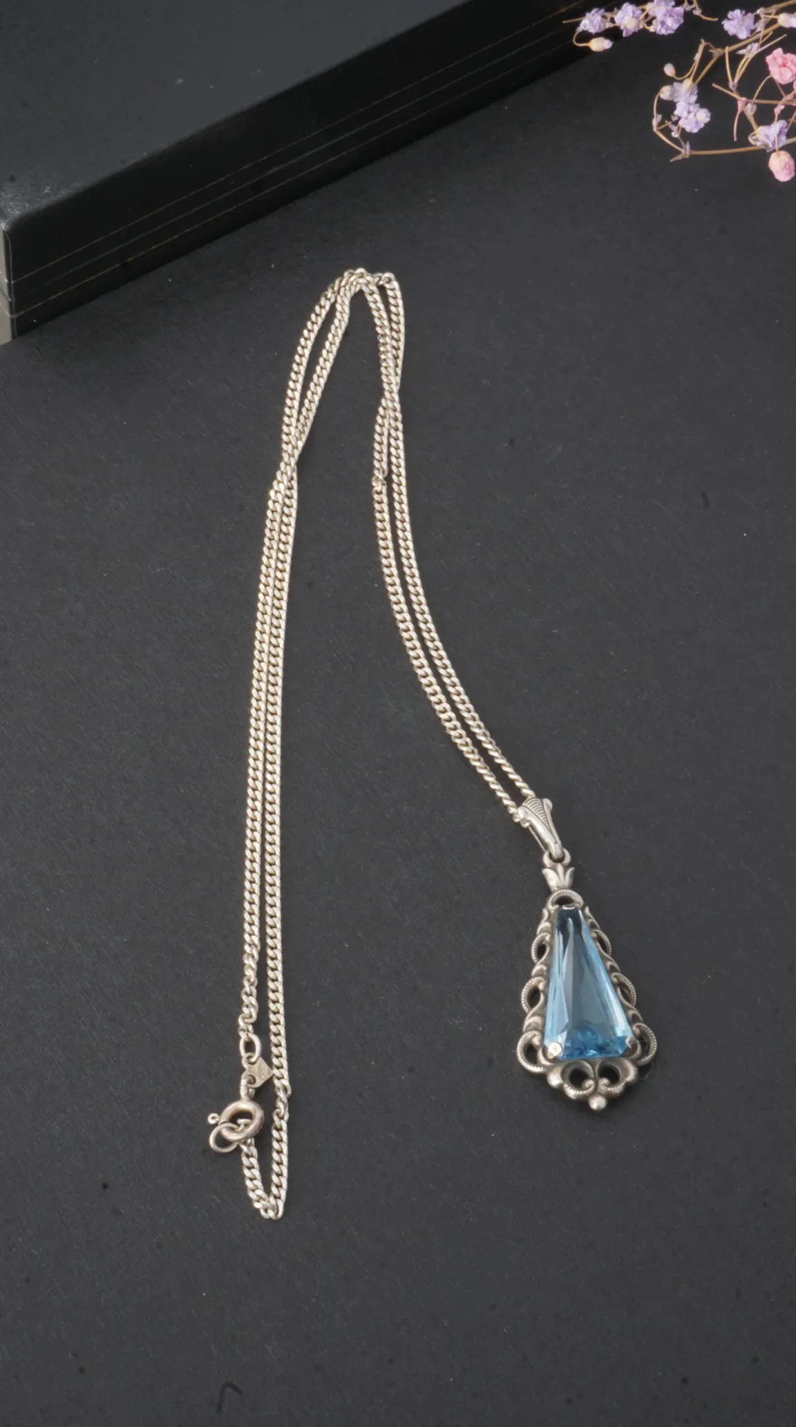 Vintage sterling silver necklace with a light blue gemstone pendant in an ornate filigree setting.