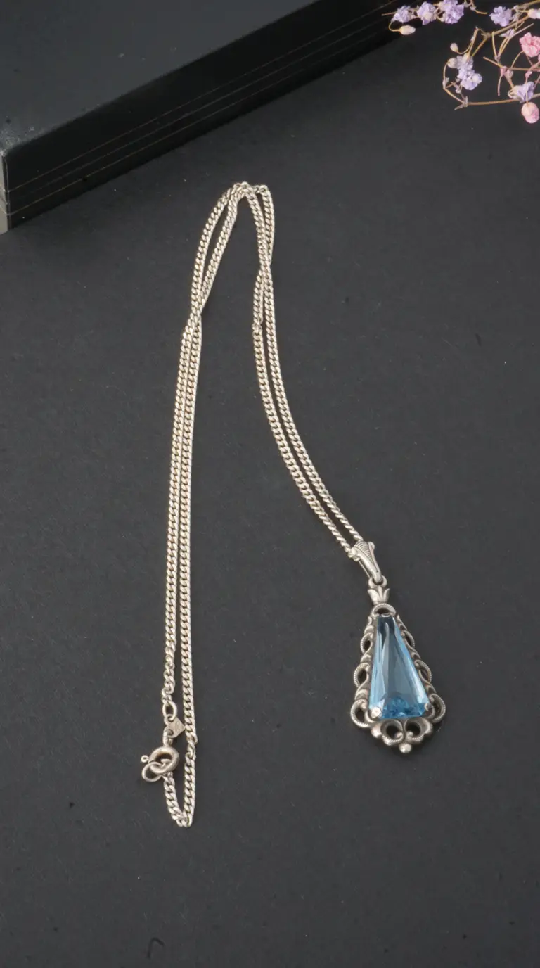 Vintage sterling silver necklace with a light blue gemstone pendant in an ornate filigree setting.