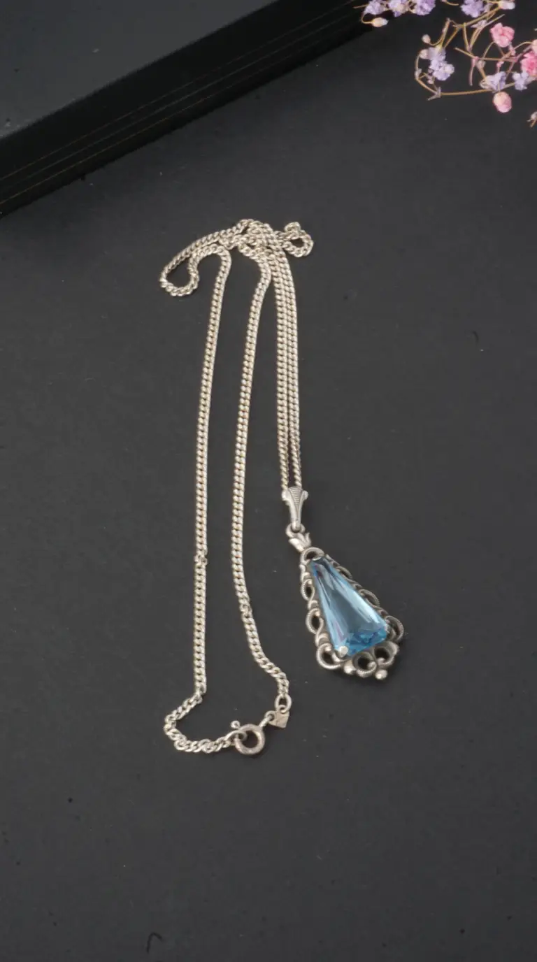 Vintage sterling silver necklace with elongated blue faceted gemstone pendant in ornate setting