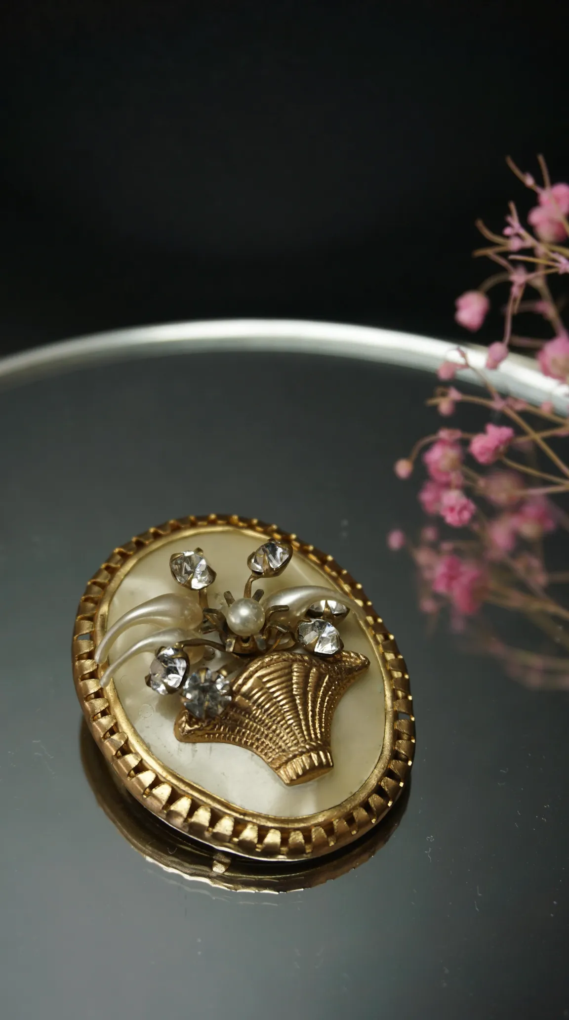Vintage gold tone brooch with mother of pearl, featuring a basket of pearl and rhinestone flowers.