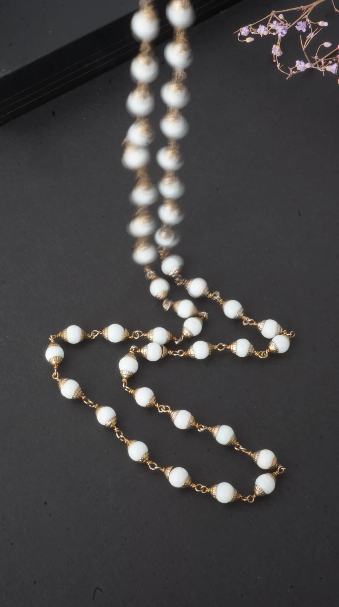 Vintage long necklace with opaque white beads and ornate gold-tone caps, antique beaded jewelry.