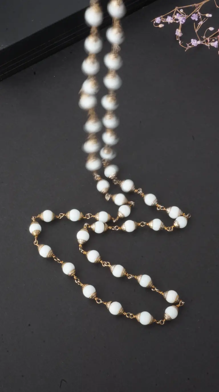 Vintage long necklace with opaque white beads and ornate gold-tone caps, antique beaded jewelry.