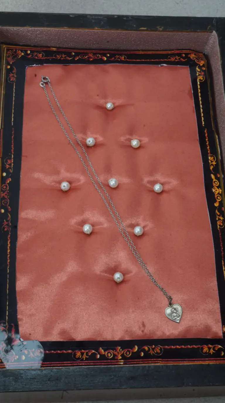 Vintage silver heart pendant necklace with angel design, displayed in ornate box with red satin lining and pearl accents.