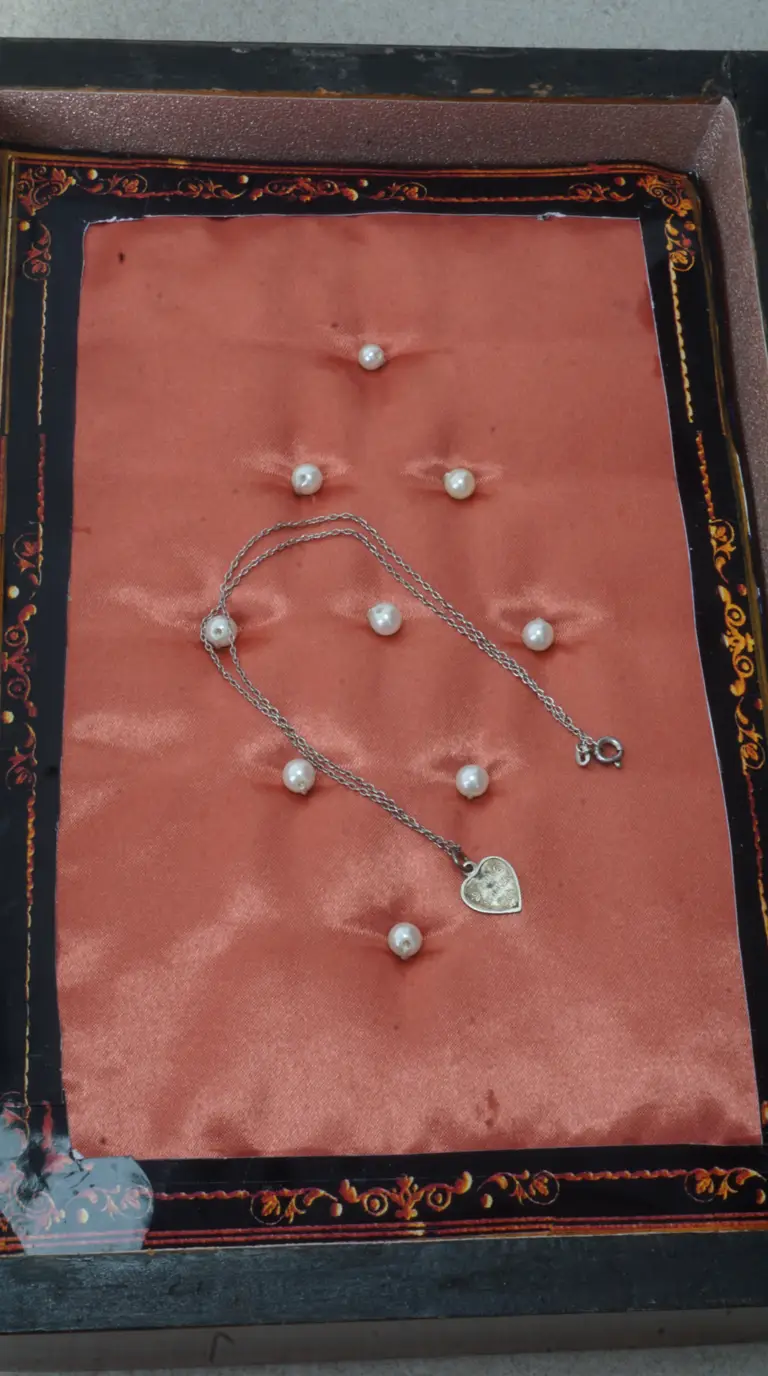 Vintage sterling silver heart pendant necklace with white pearls on salmon satin in ornate black jewelry box.