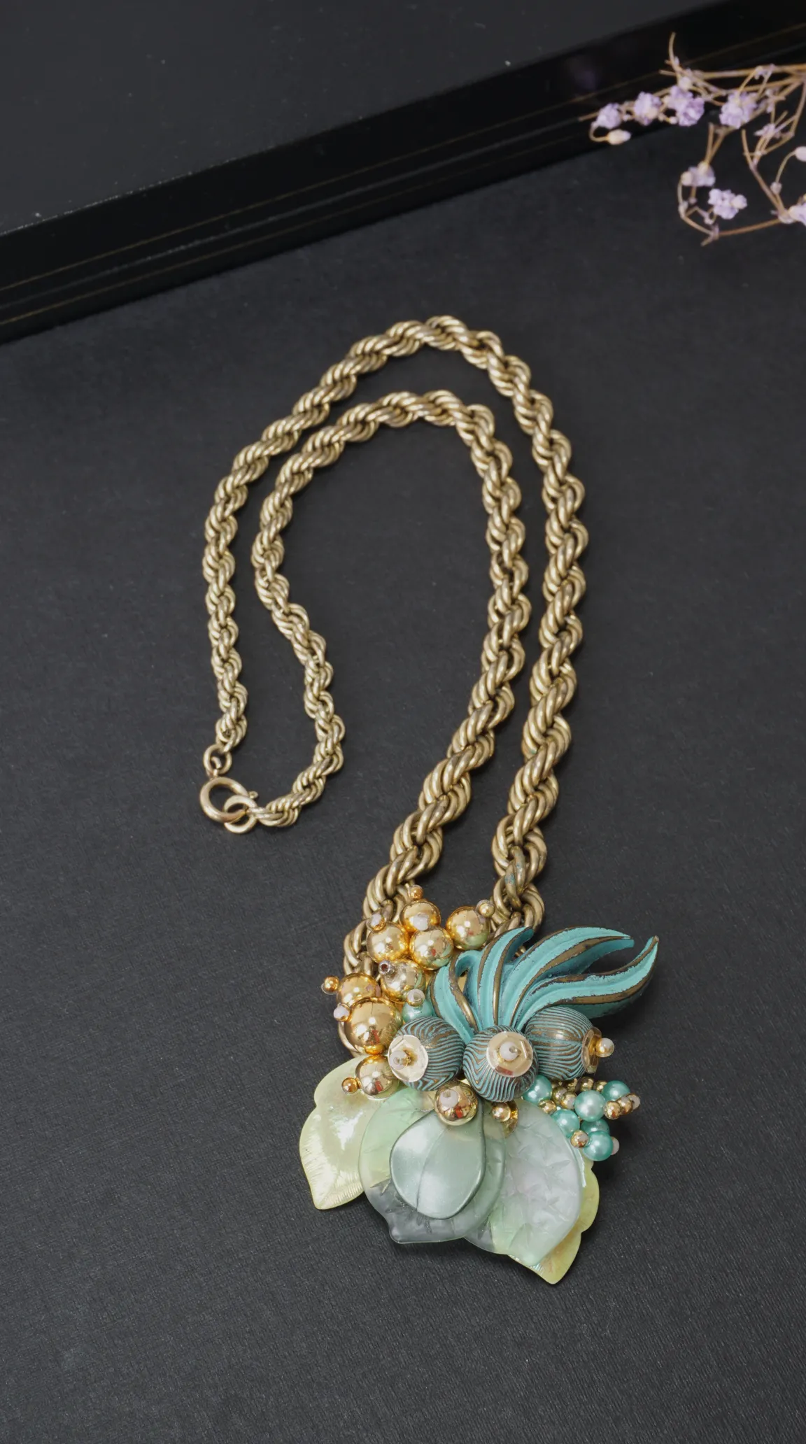 Vintage gold tone rope chain necklace with ornate teal, mint green, and gold floral cluster pendant featuring beads and leaf accents.