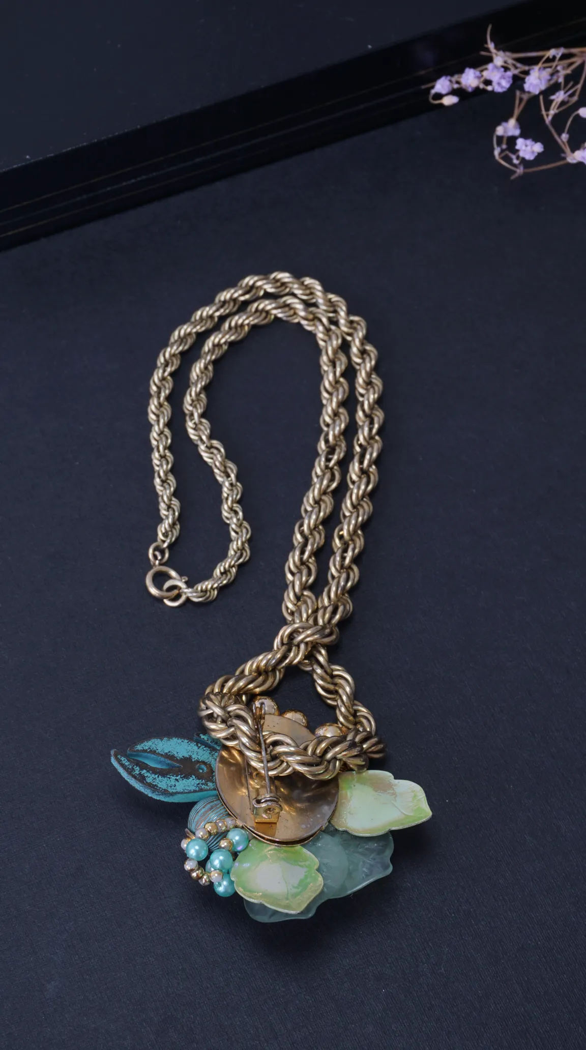 Vintage gold rope chain necklace with green and teal enamel floral and leaf pendant featuring pearl beads.