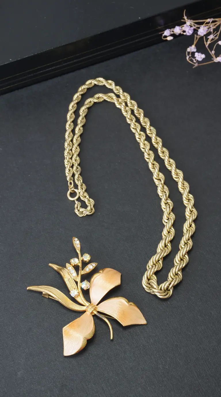 Vintage gold rope chain necklace and floral rhinestone brooch.