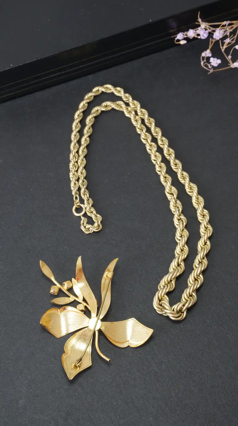 Vintage gold-tone rope chain necklace and floral leaf design brooch.