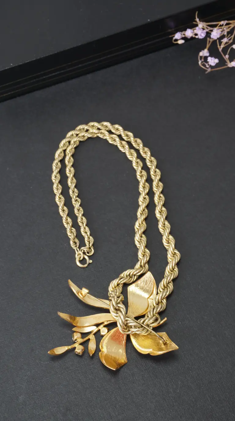Vintage gold tone rope chain necklace with ornate floral brooch pendant
