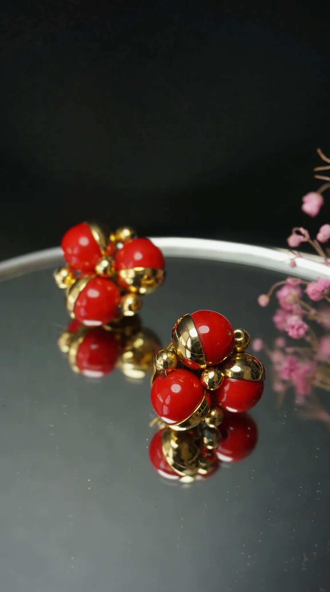 Vintage red and gold spherical cluster earrings on reflective surface