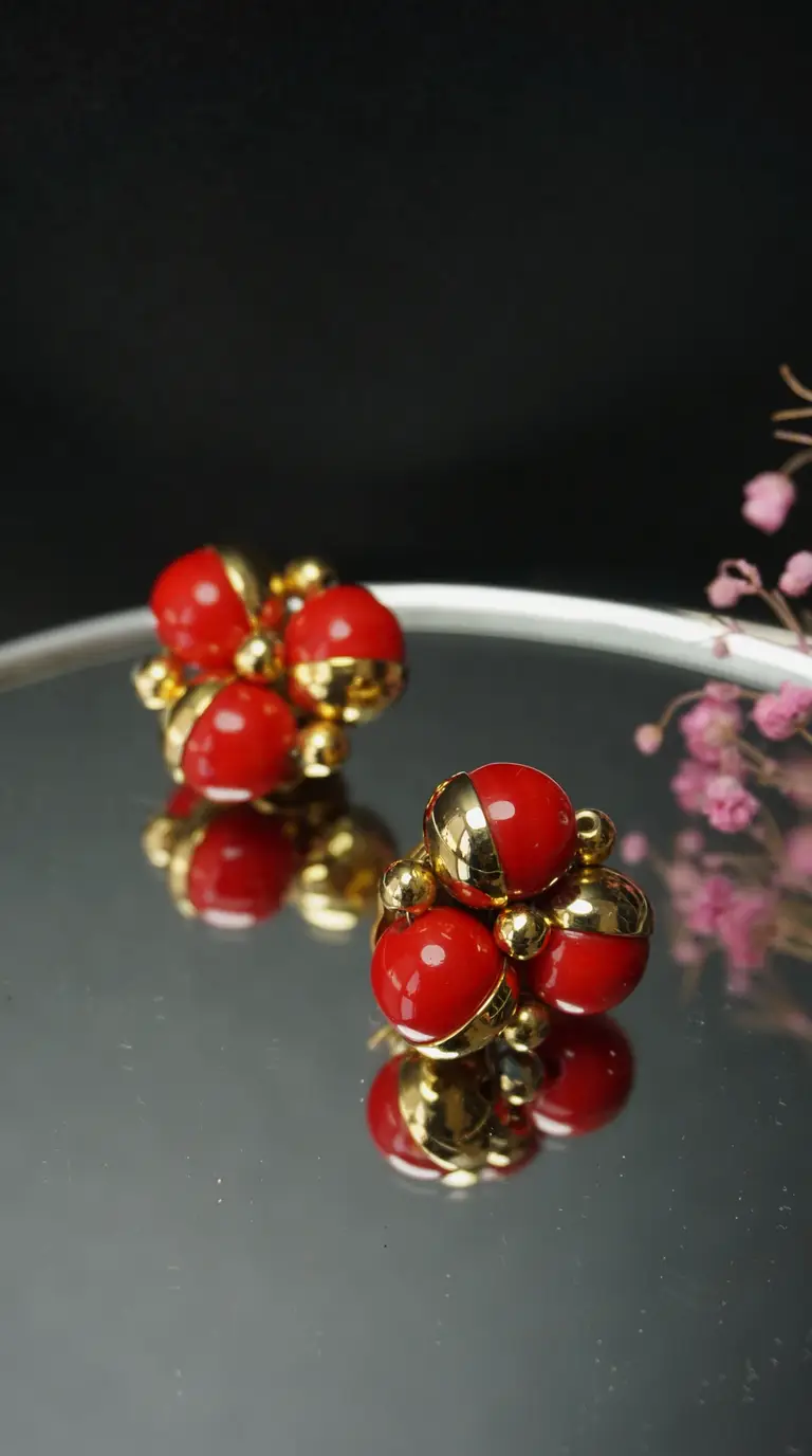 Vintage red and gold spherical cluster earrings on reflective surface