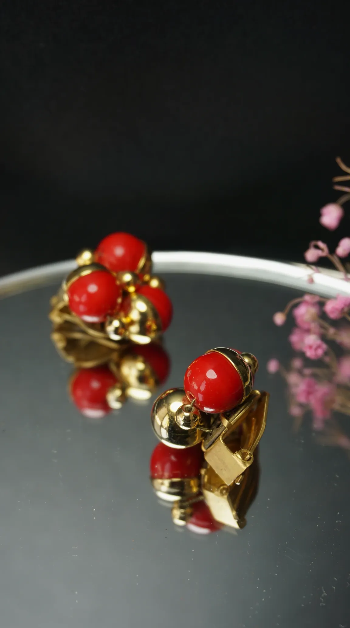 Vintage gold and red bead cluster clip-on earrings on a mirrored surface.