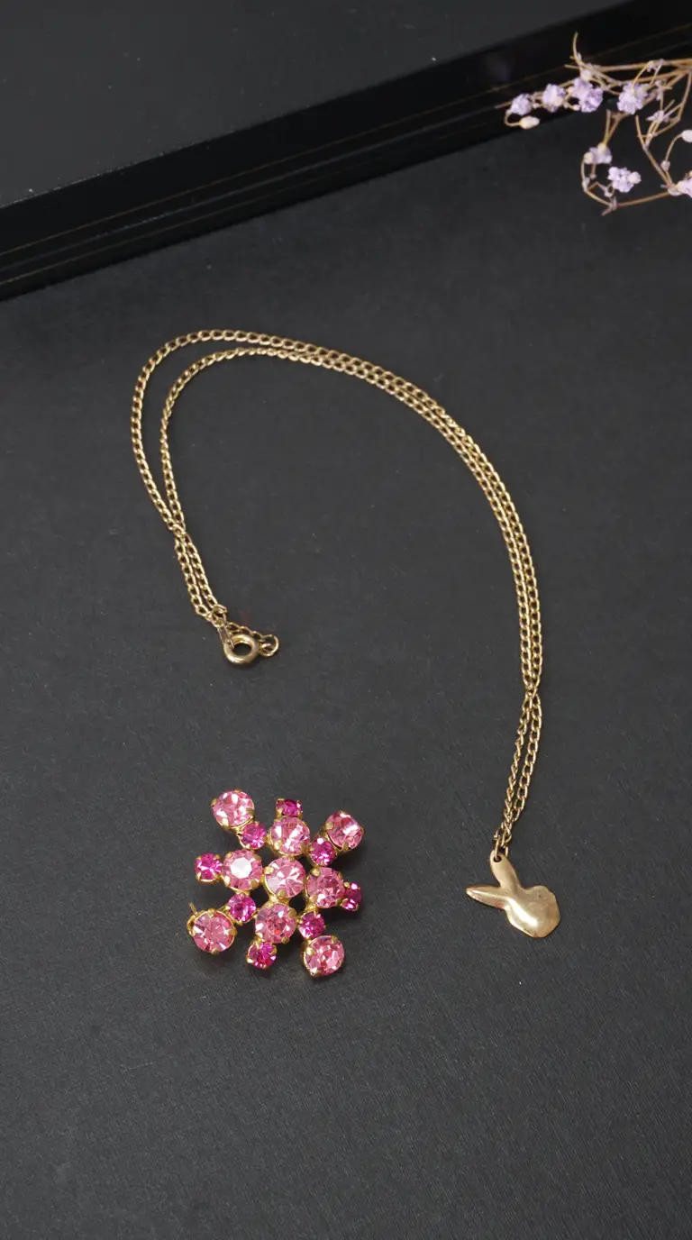 Vintage gold-tone bunny charm necklace and pink rhinestone flower brooch.