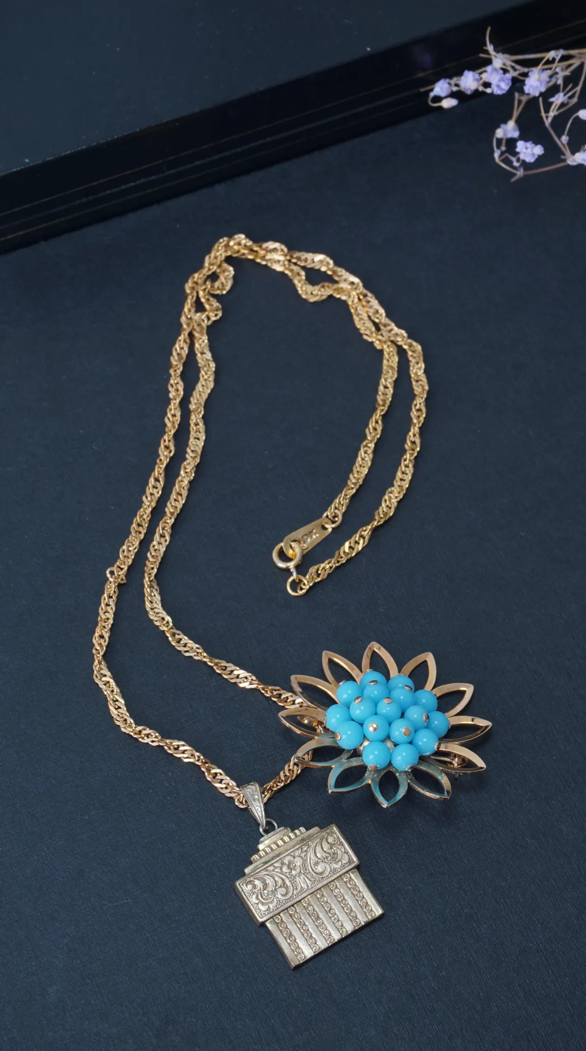 Vintage gold chain necklace with a flower pendant featuring blue turquoise beads and an embossed rectangular gold pendant.