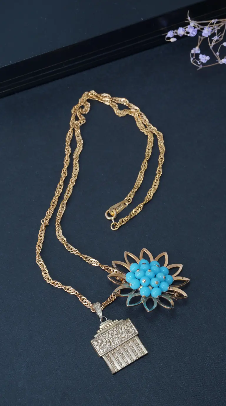 Vintage gold chain necklace with a flower pendant featuring blue turquoise beads and an embossed rectangular gold pendant.