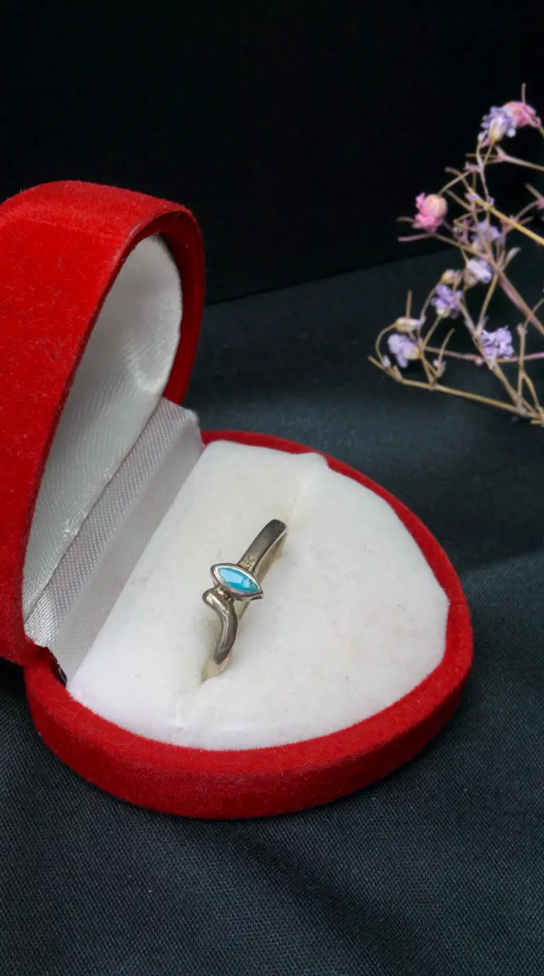 Vintage silver ring with marquise turquoise stone in red velvet heart-shaped jewelry box.