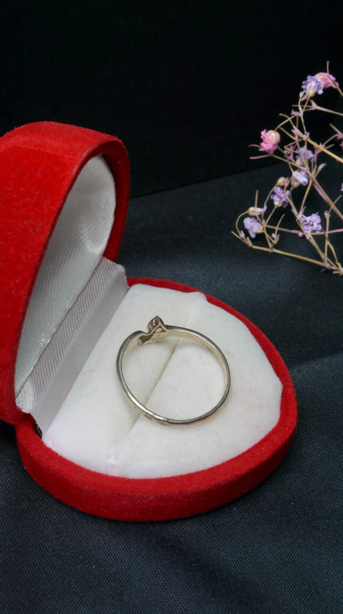 Vintage delicate silver ring in an open red velvet jewelry box with white satin lining.